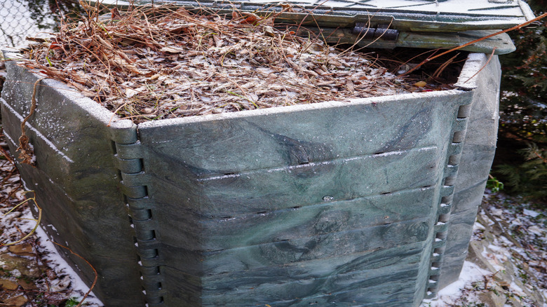 A compost bin frozen and covered in snow