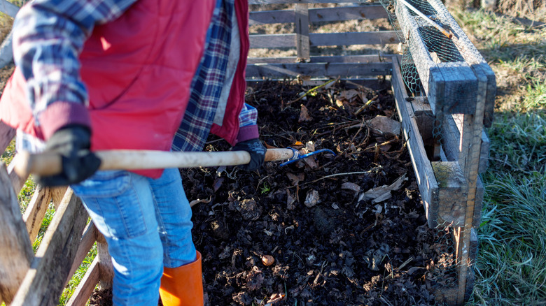 Someone turning a compost pile with a pitchfork