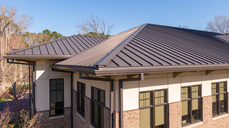 House with large windows and dark metal roof with gutter system