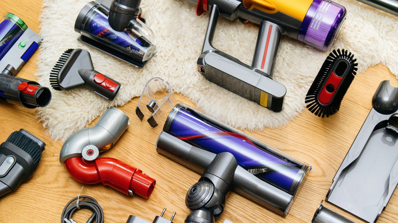 Dyson vacuum and attachment pieces laid on wood floor and white shag rug