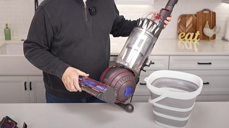 Man tilting Dyson Animal vacuum sideways on countertop