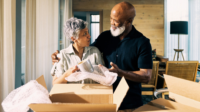 Older man and woman couple packing boxes of dishes