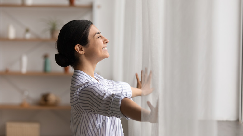 woman opening curtains
