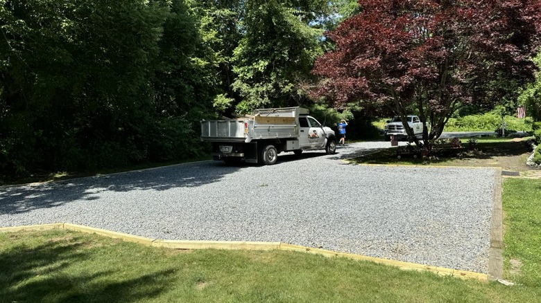 A truck parked on gravel driveway surrounded by landscaping timbers
