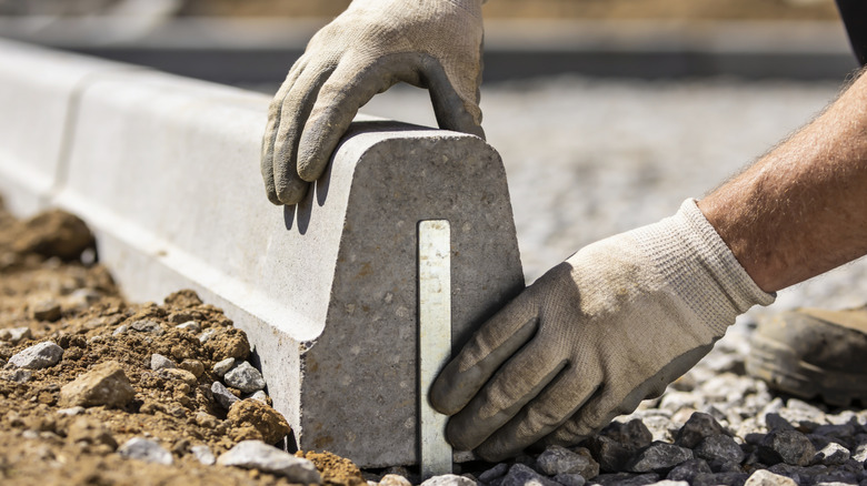 Person installing a curb along a driveway edge