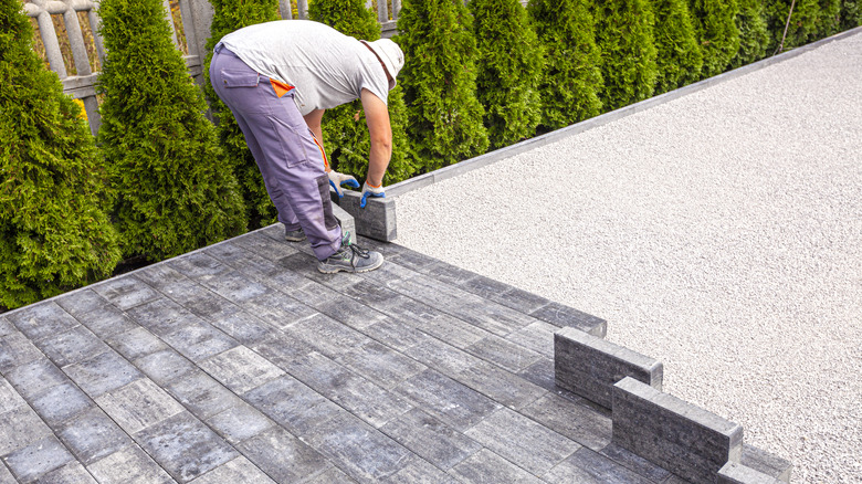Person laying gray pavers on a driveway