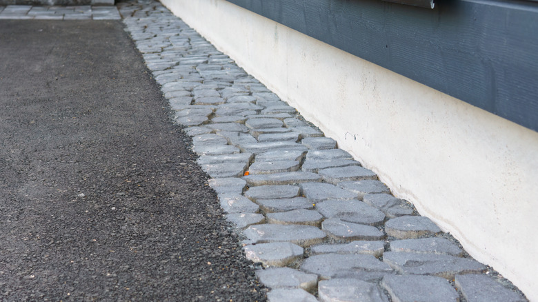 A gray stone border defines an asphalt driveway