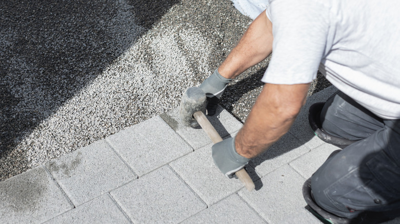 A landscaper installs a permeable driveway by laying blocks over a substrate