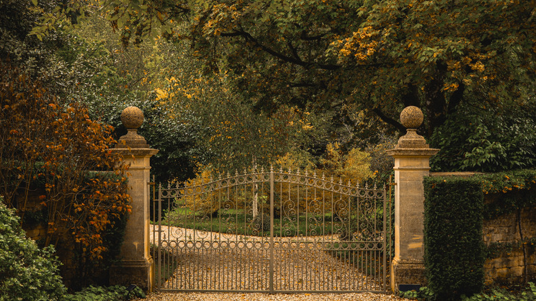 driveway of an old mansion with gravel and a gate