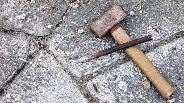 A hammer and chisel sitting on old paver layout