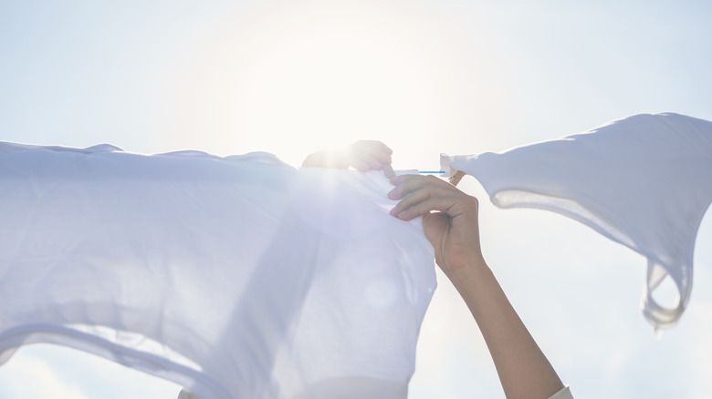 Hands placing laundry on outdoor clothes line on sunny day