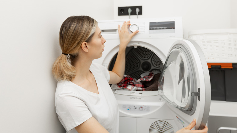 A woman adjusting the settings on her clothes dryer