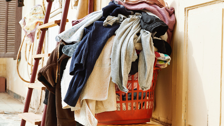 An overflowing laundry basket in a basement laundry room