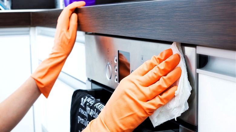 Person cleaning oven wearing gloves