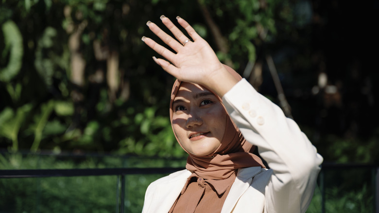 Woman using hand to block sunlight in her face