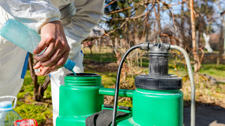 Gardener mixing chemicals in protective suit