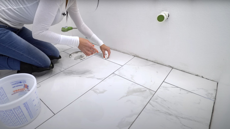 woman rinsing sealed white marble-style tiles