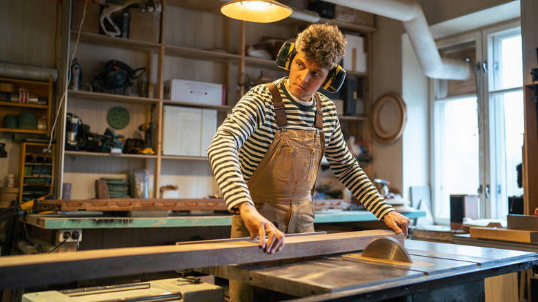person cutting a piece of wood with a table saw