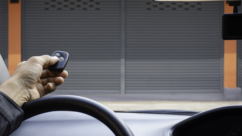 Person uses a garage opener remote to activate their wall-mounted garage door opener.