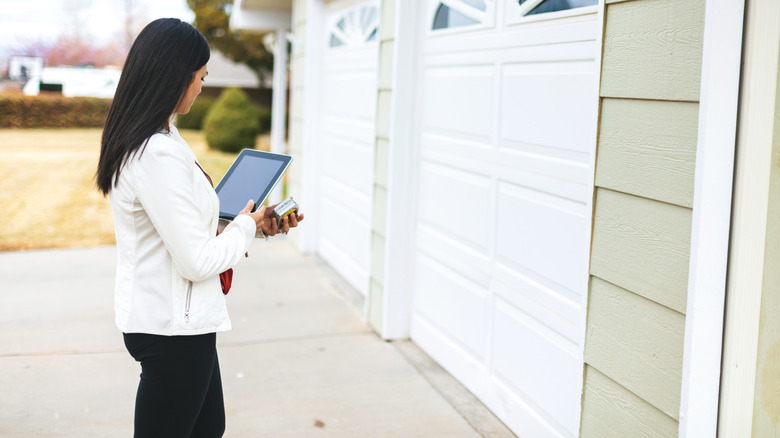 Woman using an iPad as a remote to open her garage door via Wi-Fi.