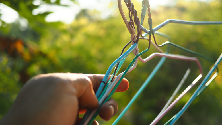 Hand holding old wire hangers outside.