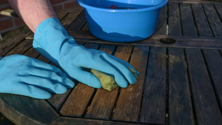 Gloved hand scrubbing wooden table