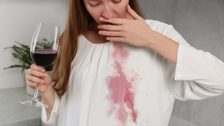 Woman accidentally stains her white blouse with red wine.