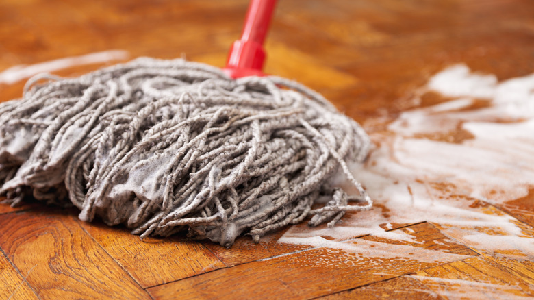 Mopping wood floors with soapy water.