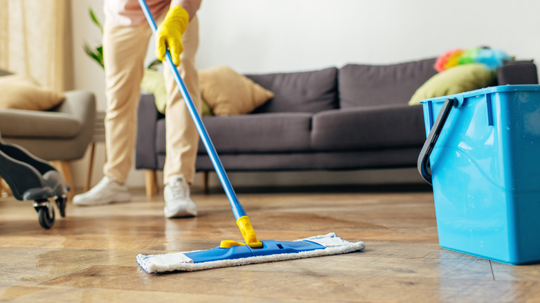 A person cleaning wooden floors with a flat mop.