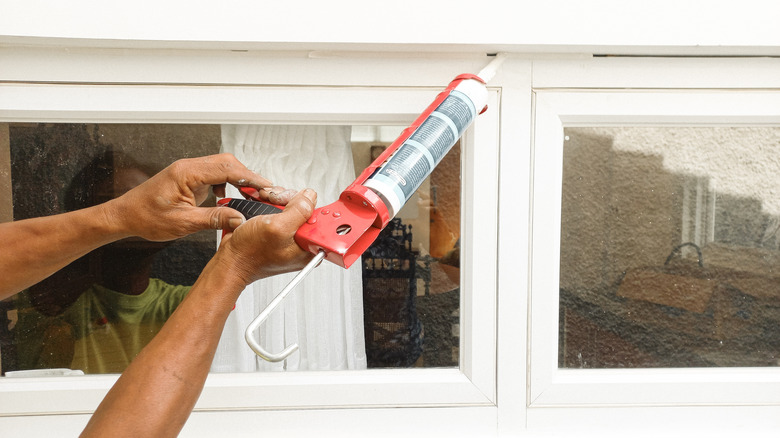 Man's hands applying caulk