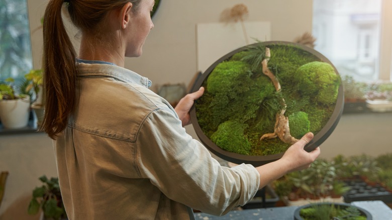 Woman holding moss in circular frame