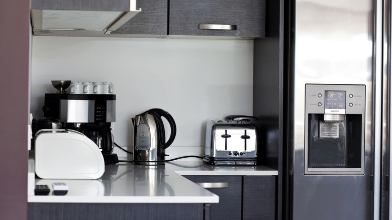 small appliances arranged on a kitchen countertop next to fridge
