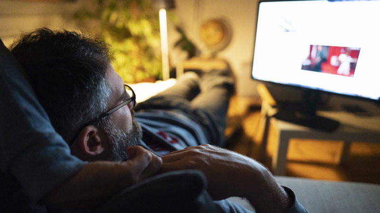 Man watching a TV while lying on the couch