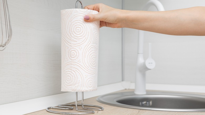 Woman's hand removing a paper towel from a metal holder
