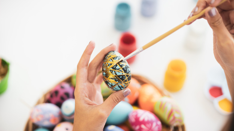 A hand painting an Easter egg
