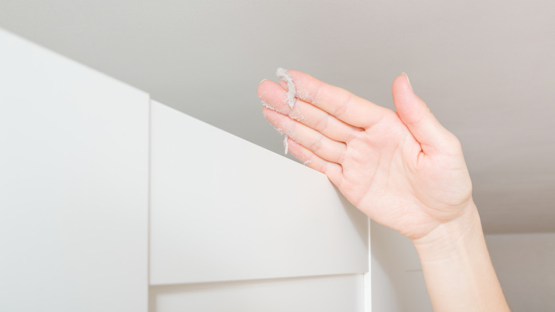 Hand wiping dust on cabinet