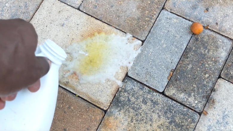 Person pouring muriatic acid on paver rust stain