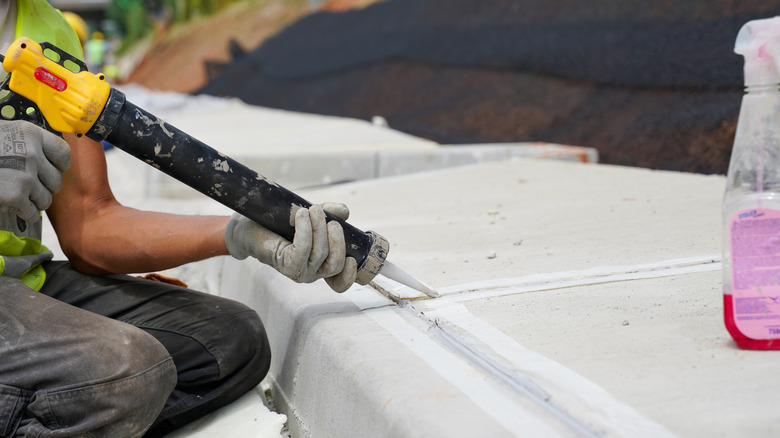 person using sealant on cement