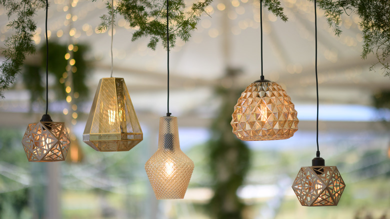 Various lamps hanging from the ceiling surrounded by decorative branches.