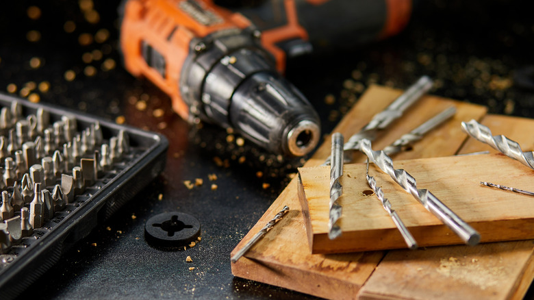 Drill and drill bits scattered on pieces of wood
