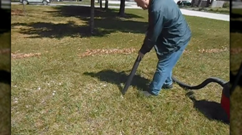 A person sucking up gravel with a vacuum hose attachment