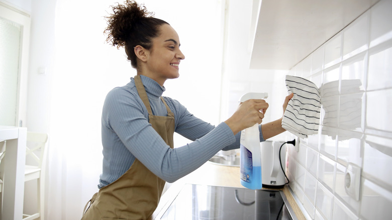 Woman wipes kitchen backsplash