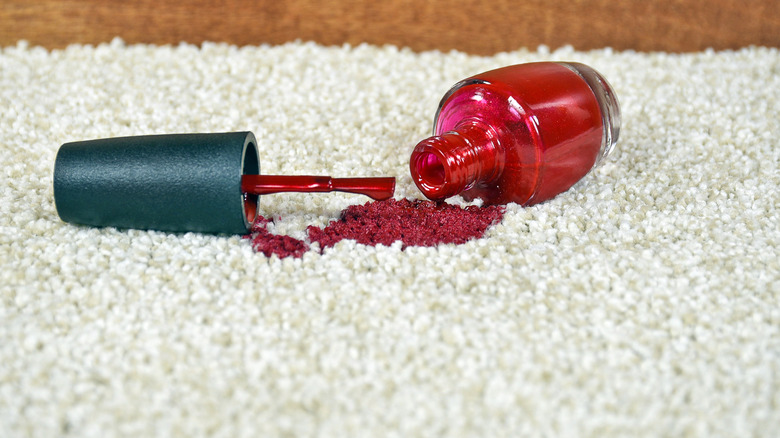 Bottle of red nail polish spilled and staining a carpet