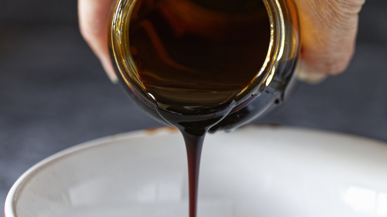 hand pouring molasses into a white bowl