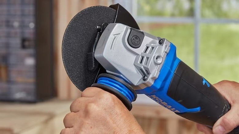 A person holding a Kobalt angle grinder