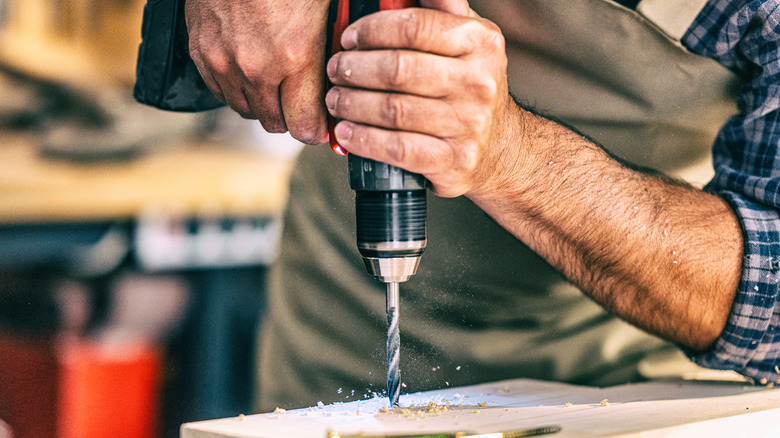 A carpenter drilling a hole in a piece of wood