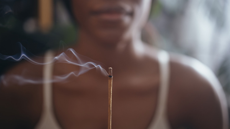 A woman holding a lit incense stick.