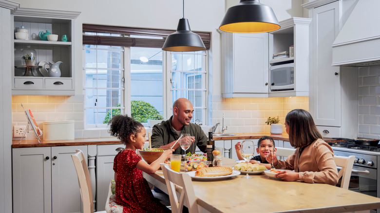 a family of four eats at a dining table in a small kitchen