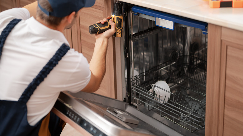 man unmounting dishwasher