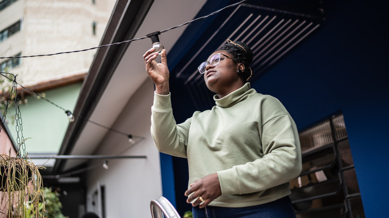 woman changing exterior light bulb